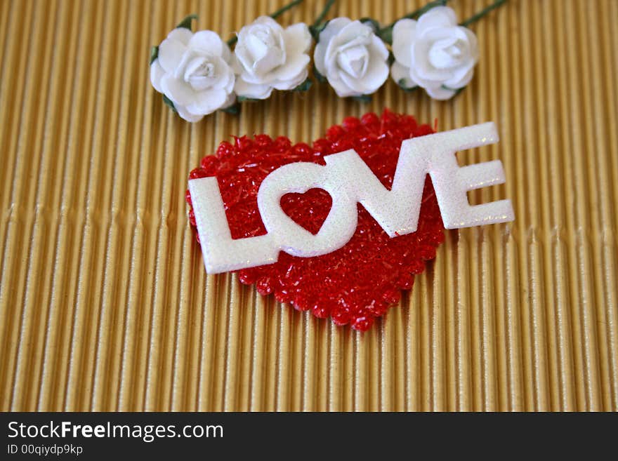 The word love on a soft red heart with white roses. The word love on a soft red heart with white roses