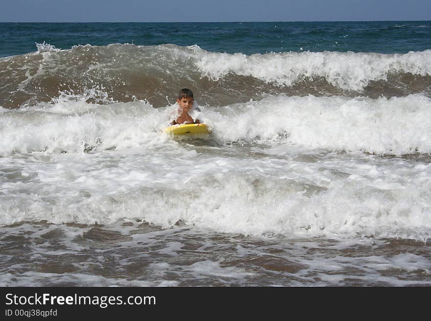 Little boy surfing some waves at the beach