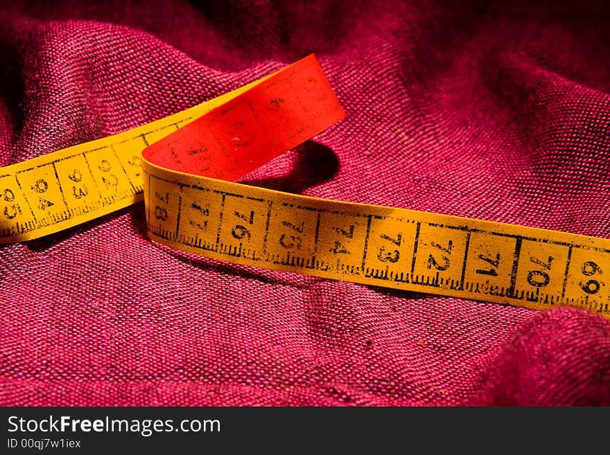 Tailor's metric tape macro close up red background. Tailor's metric tape macro close up red background