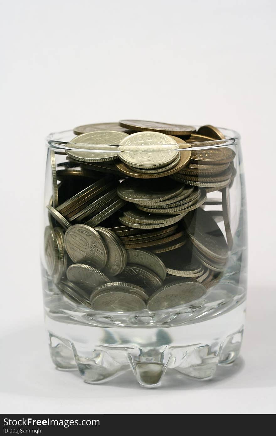 Close-up of multicolor coins in glass on the white background (isolated on white)