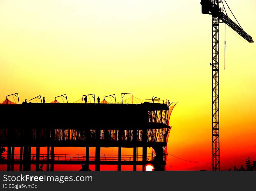 Workers on a construcion site at sunset. Workers on a construcion site at sunset