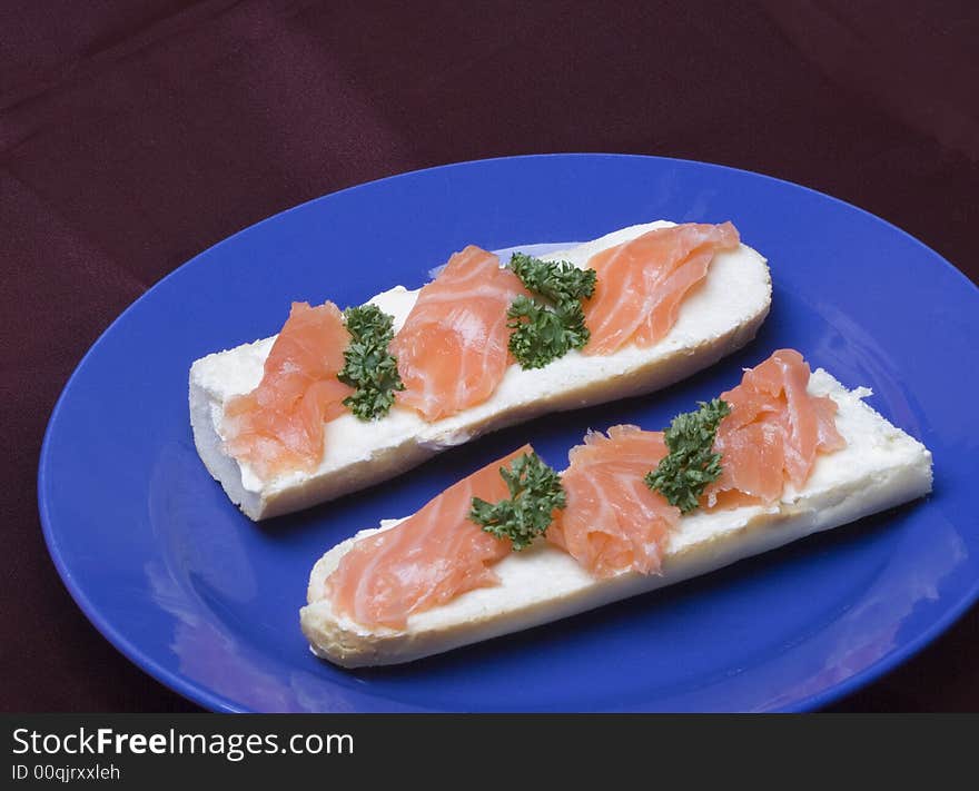 Smoked salmon on French bread on the blue plate