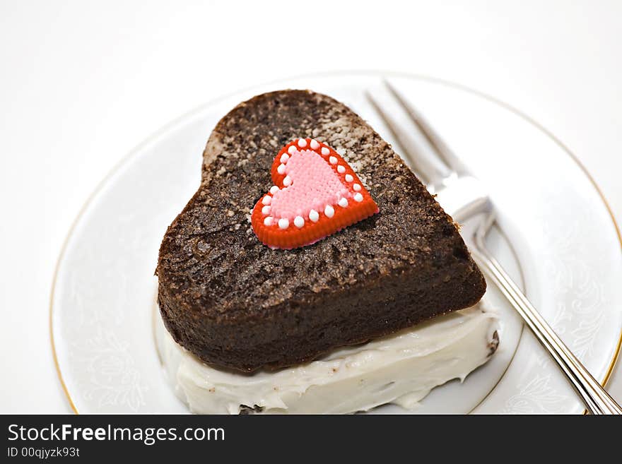 A heart shaped chocolate cake on plate with fork. A heart shaped chocolate cake on plate with fork.