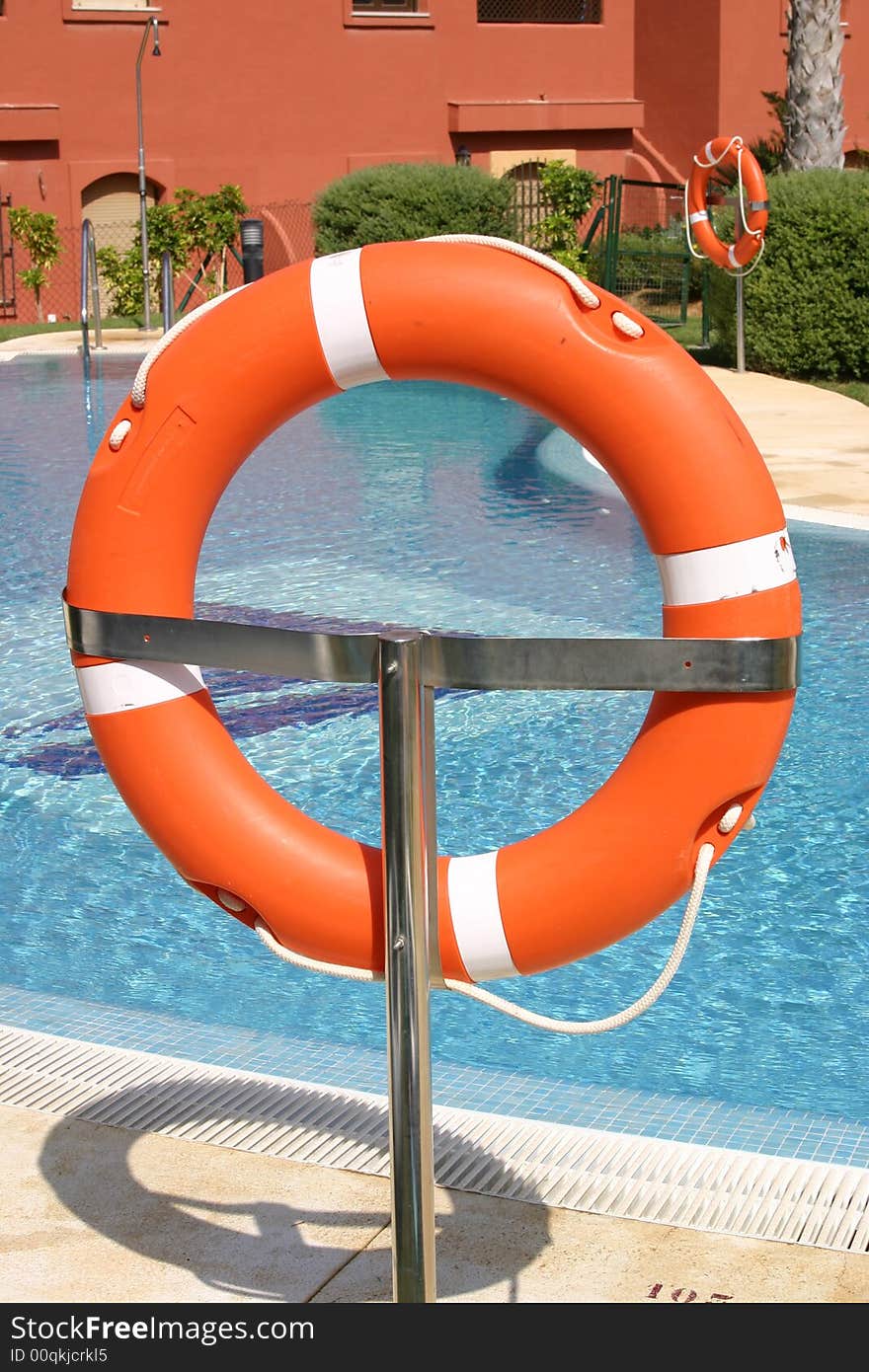 A life saving ring on a stand next to a swimming pool. A life saving ring on a stand next to a swimming pool