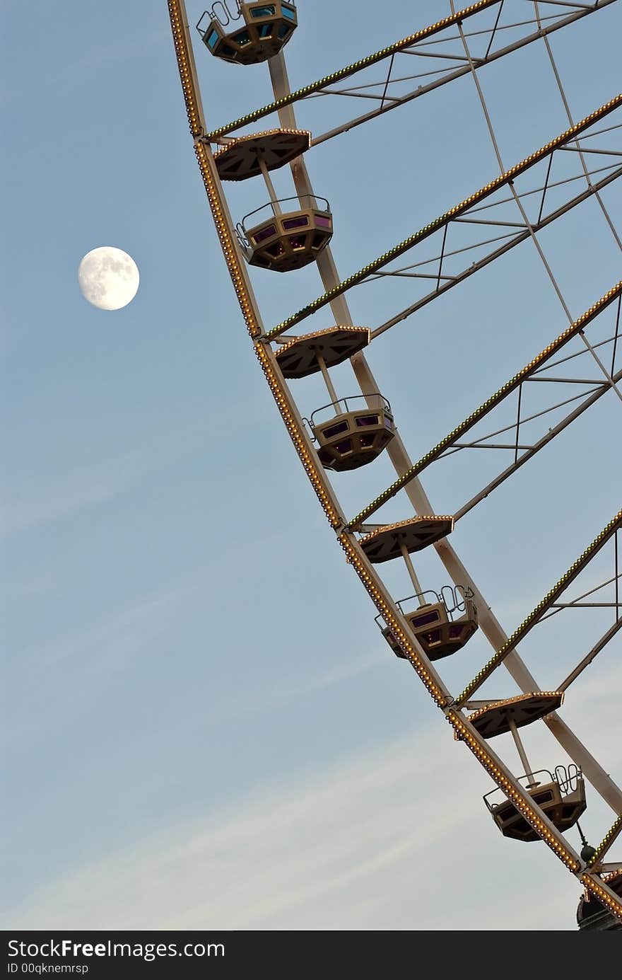 Ferris Wheel against cloudy blue sky (detail) with full moon. Ferris Wheel against cloudy blue sky (detail) with full moon