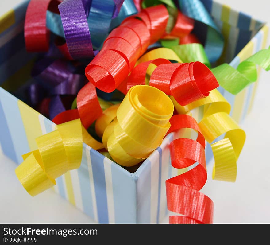 Curly ribbon in bright colours in a striped gift box. Curly ribbon in bright colours in a striped gift box.