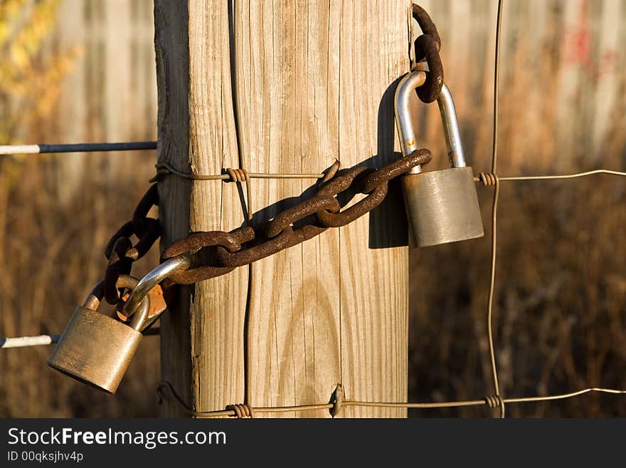 Old rusty locks and a chain on a wire and post fence. Old rusty locks and a chain on a wire and post fence