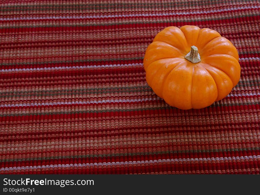 Small orange pumpkins on decorative cloth background.