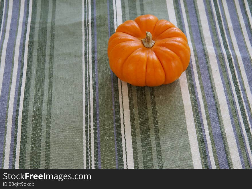 Small orange pumpkins on decorative cloth background.