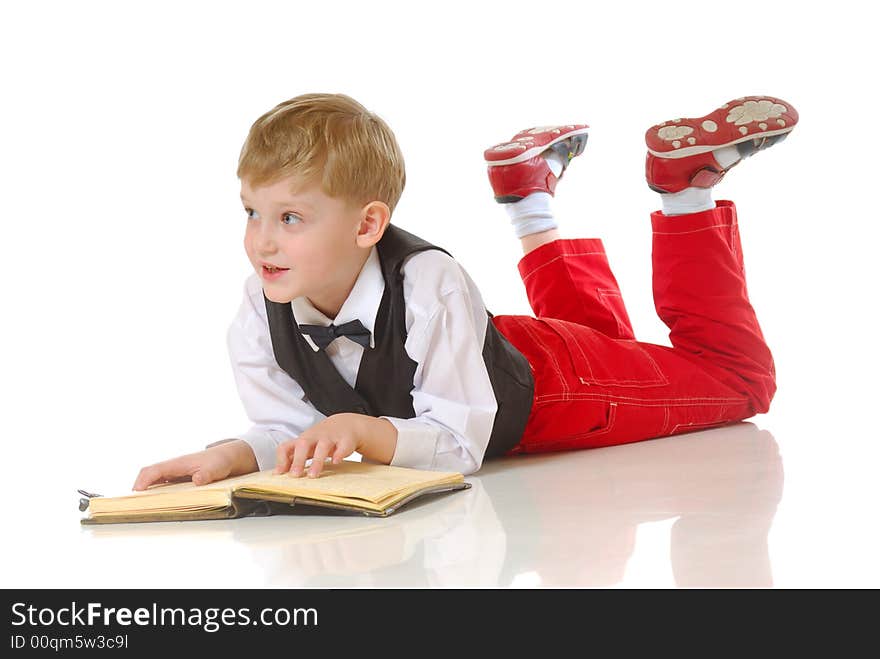 Young boy in smart clothes lying on ground reading book, white studio background. Young boy in smart clothes lying on ground reading book, white studio background.