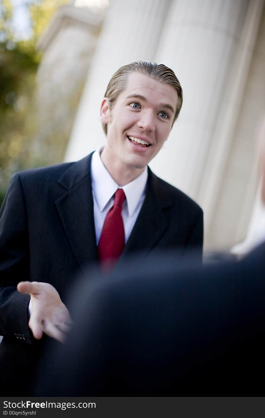 Over the shoulder view of businessman standing in front of another businessman explaining something