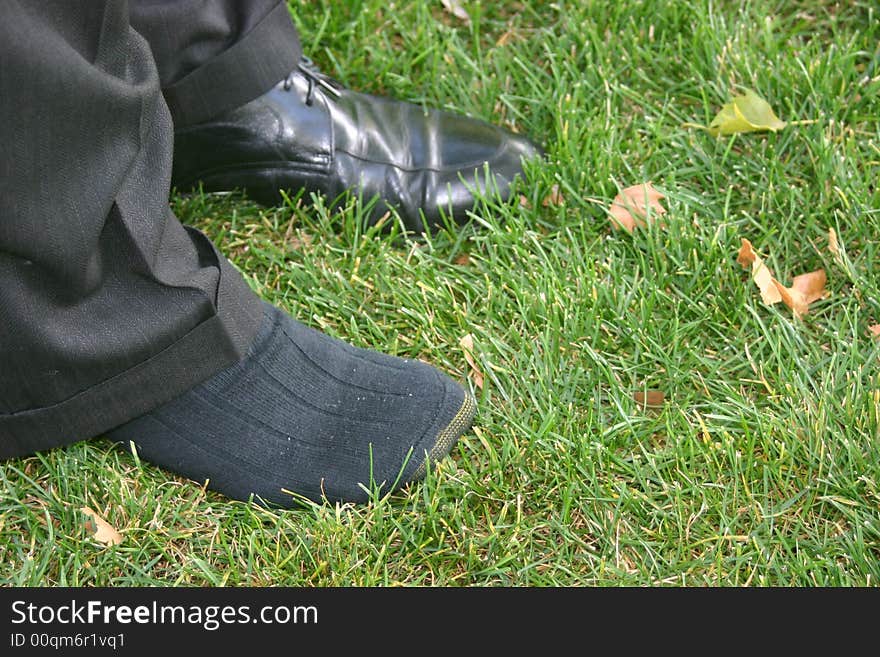 Business feet in grass without one shoe on. Business feet in grass without one shoe on