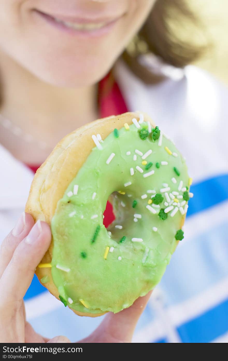 Close view of woman smiling and holding donut near face. Close view of woman smiling and holding donut near face