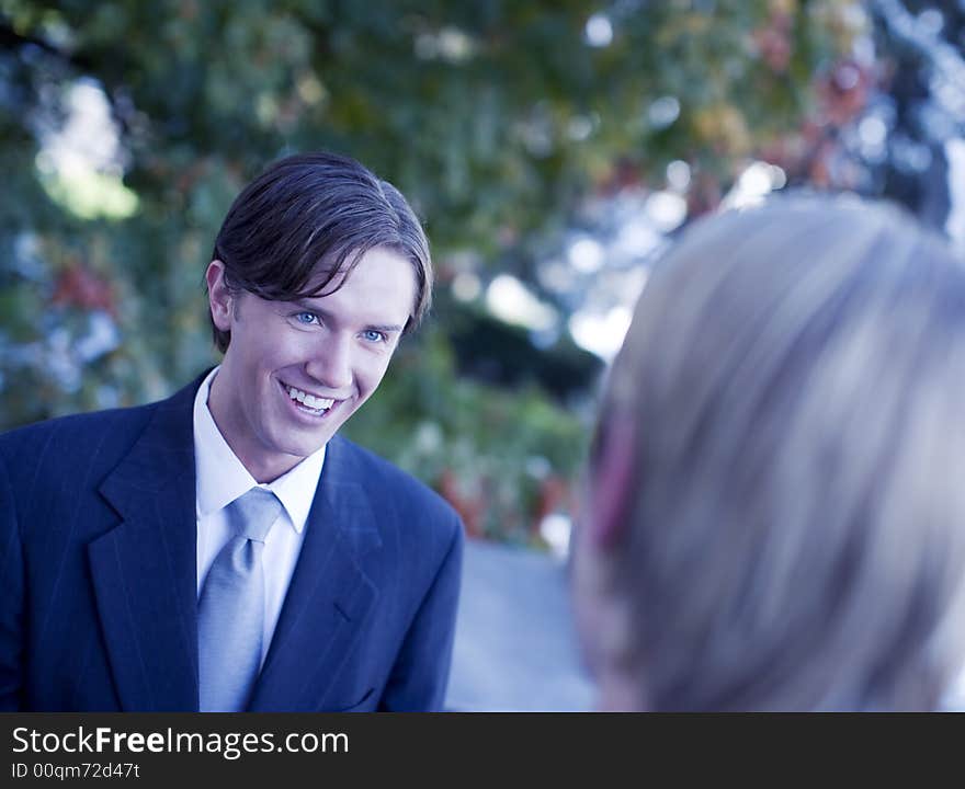 Over shoulder view of businessman standing in suit and tie smiling. Over shoulder view of businessman standing in suit and tie smiling