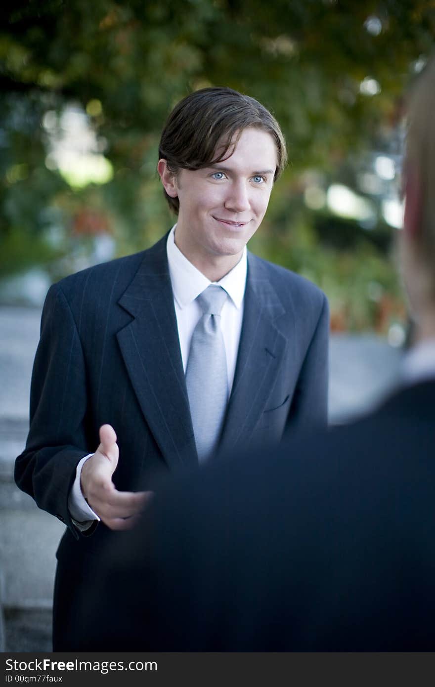 Over shoulder view of businessman standing in suit and tie talking. Over shoulder view of businessman standing in suit and tie talking