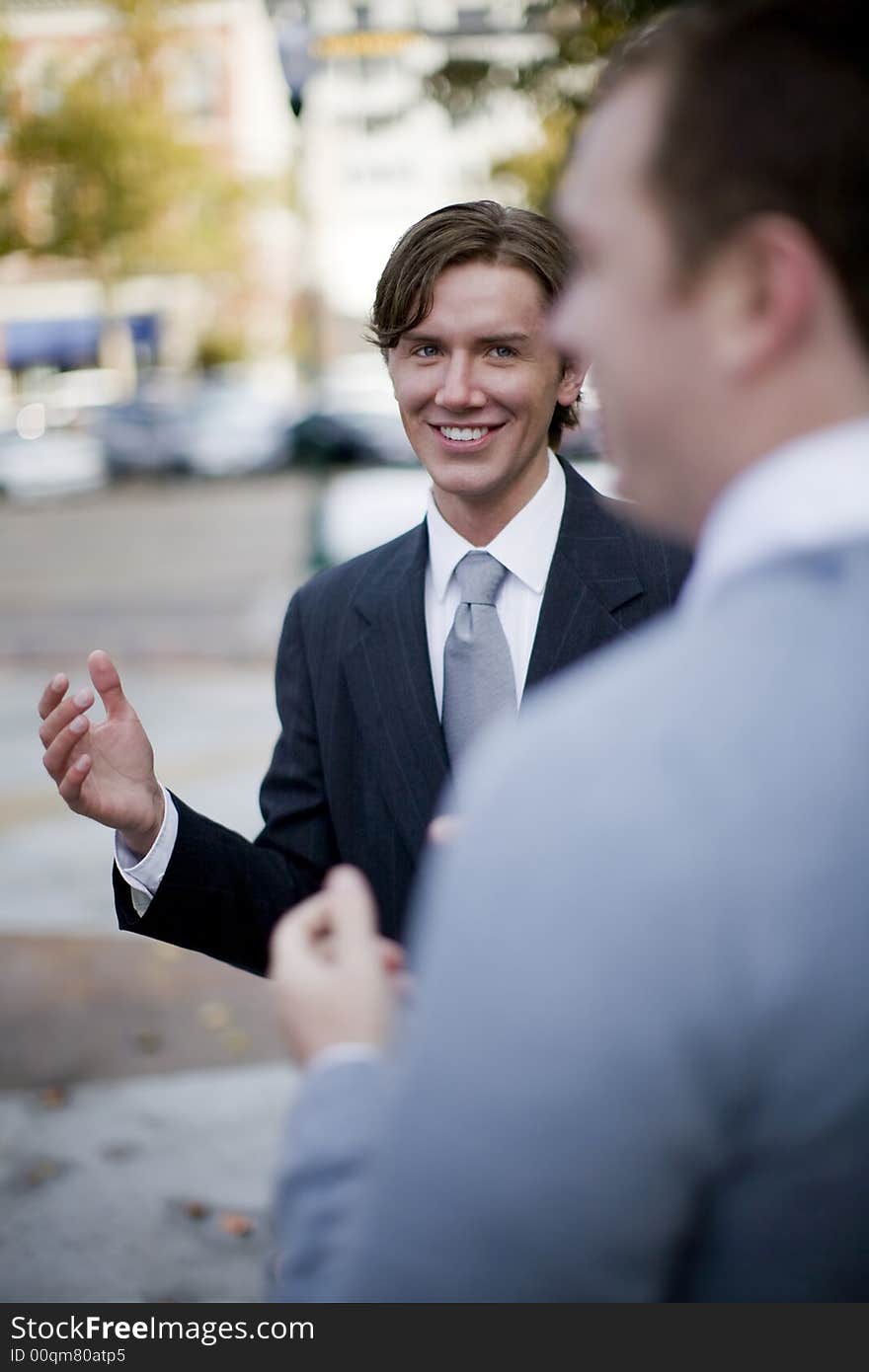 Over shoulder view of businessman standing in suit and tie talking. Over shoulder view of businessman standing in suit and tie talking