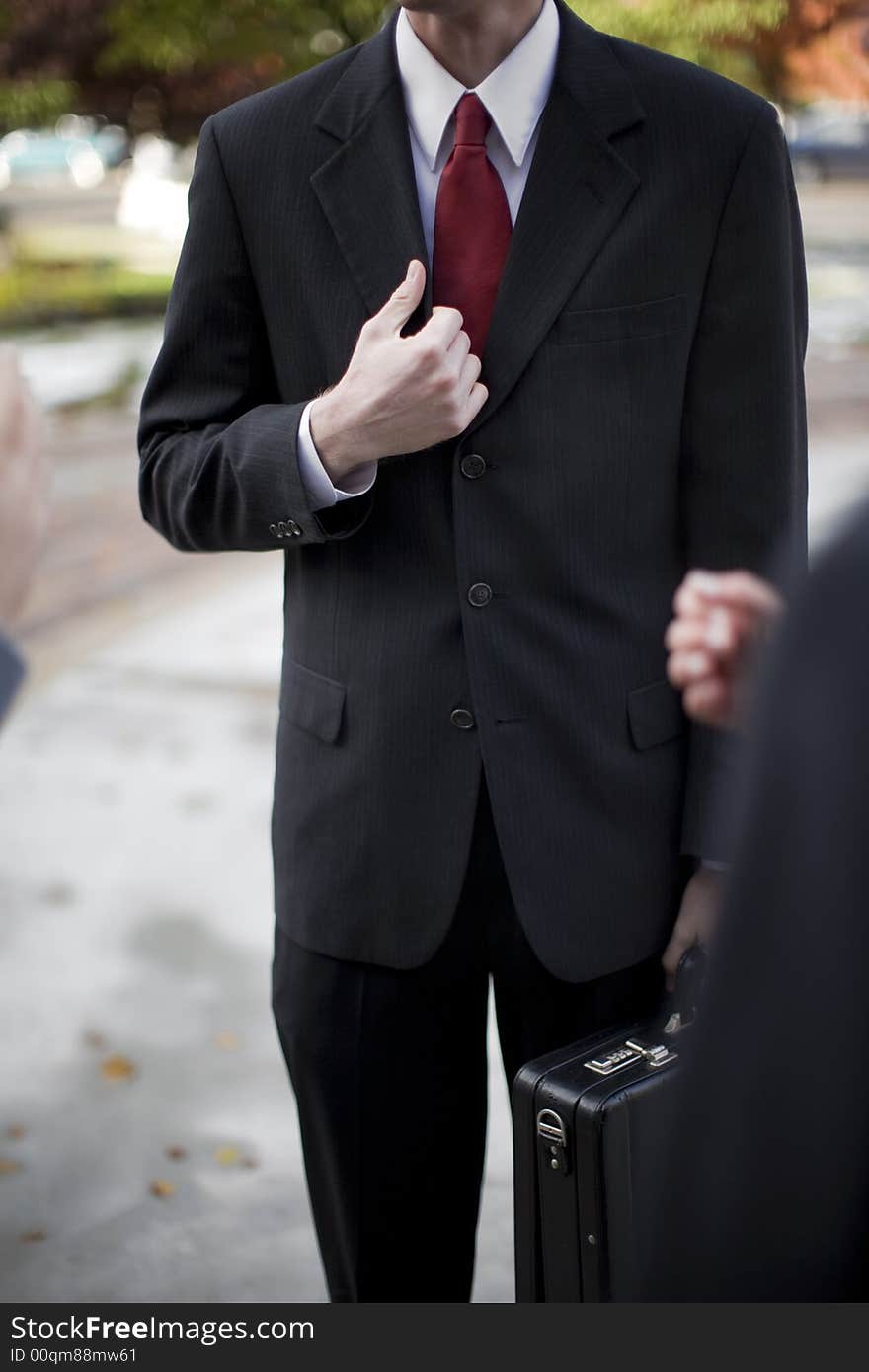 Over shoulder view of businessman in suit standing holding briefcase and part of his jacket