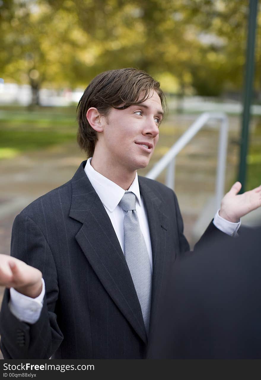 Over shoulder view of businessman standing in suit and tie with both hands up in air. Over shoulder view of businessman standing in suit and tie with both hands up in air