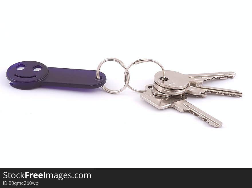 Bunch of keys with dark blue smile trinket isolated on white. Close-up. Bunch of keys with dark blue smile trinket isolated on white. Close-up.