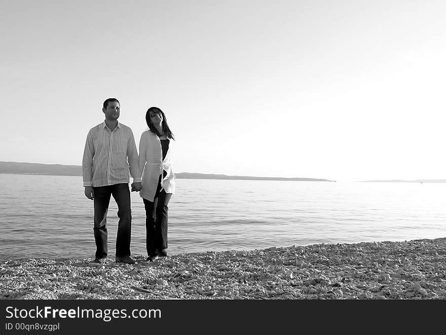 An attractive young couple walking along a beach. An attractive young couple walking along a beach.