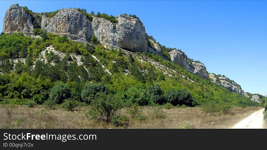 Panoramic Image of the Hill Covered by Green Forest and the Sandy Road. Panoramic Image of the Hill Covered by Green Forest and the Sandy Road