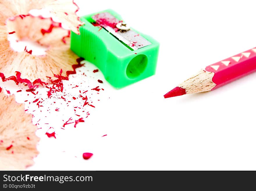 Sharpened red pencil with green sharpener in background and pencil shavings