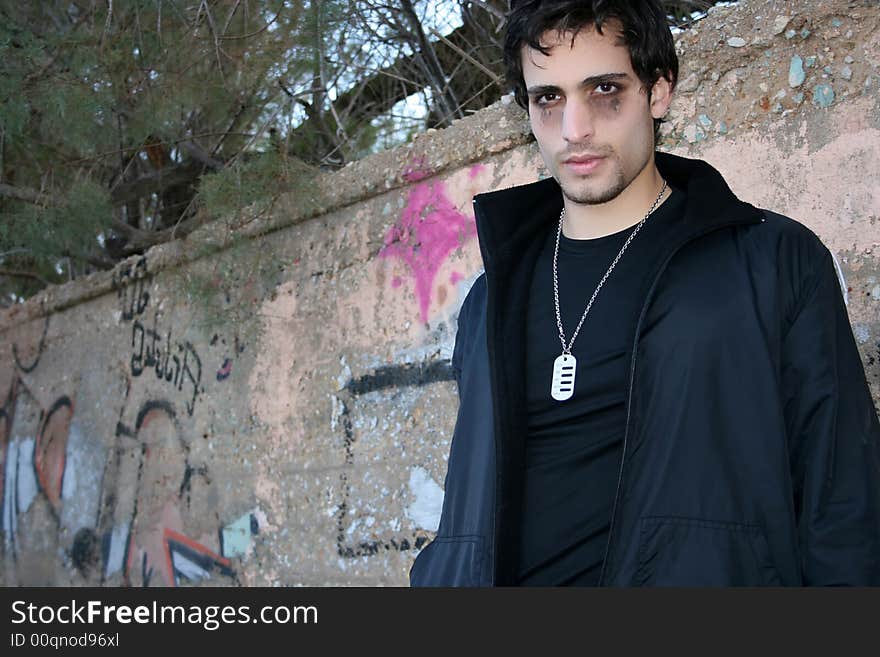 Young man in gothic look lying on a wall