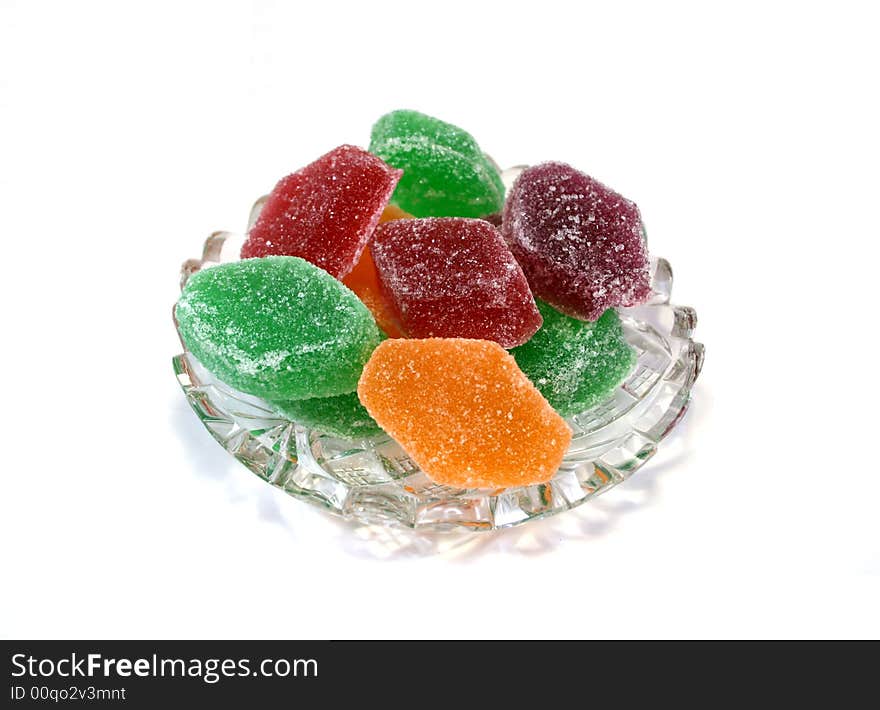 Fruit candies of different colors on crystal cut plate