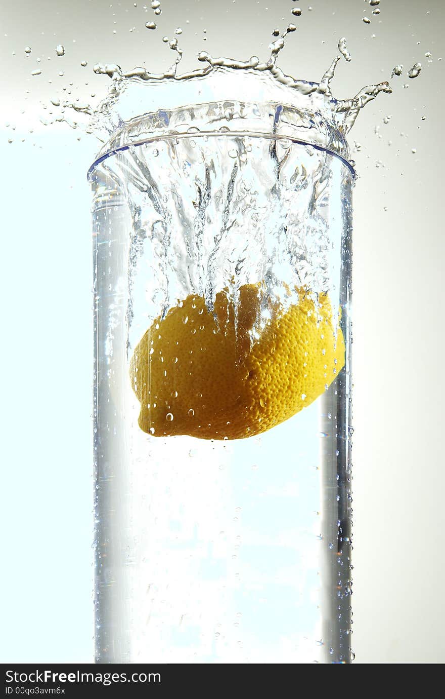 A lemon splashing into a container of water.