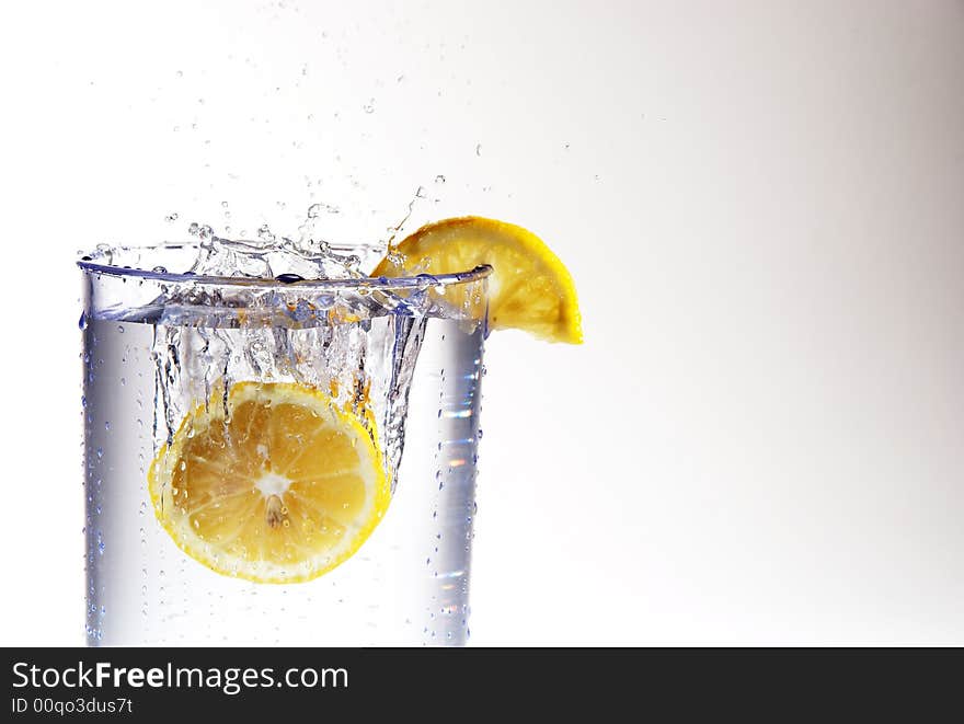 A lemon dropping into a glass of water. A lemon dropping into a glass of water.