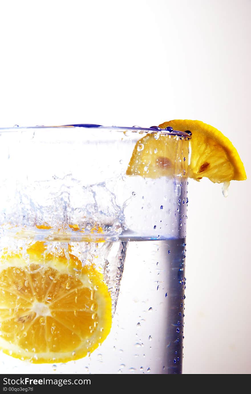 A lemon dropping into a glass of water. A lemon dropping into a glass of water.