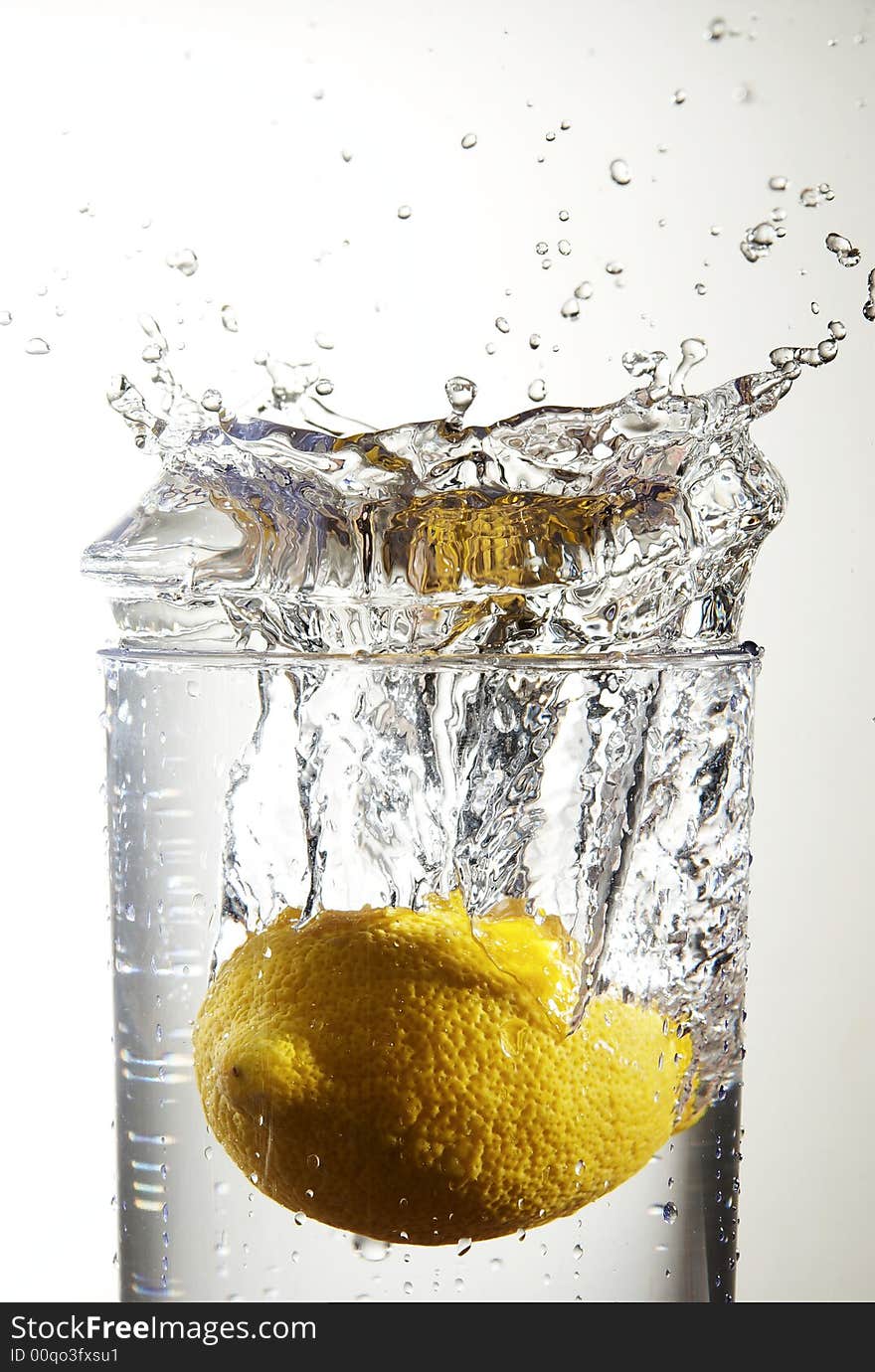 A lemon dropping into a  glass of water. A lemon dropping into a  glass of water.