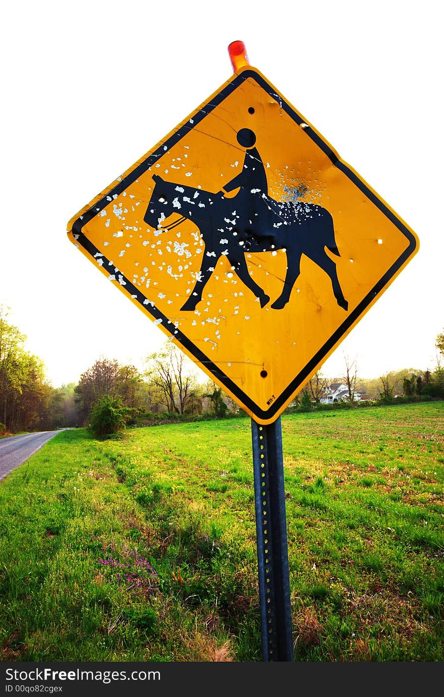 A horse crossing sign that has been shot up by vandals. A horse crossing sign that has been shot up by vandals.