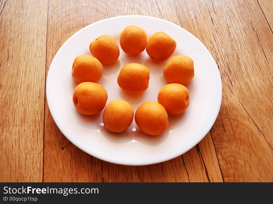 Apricots on the white plate, standing on the wooden table. Apricots on the white plate, standing on the wooden table