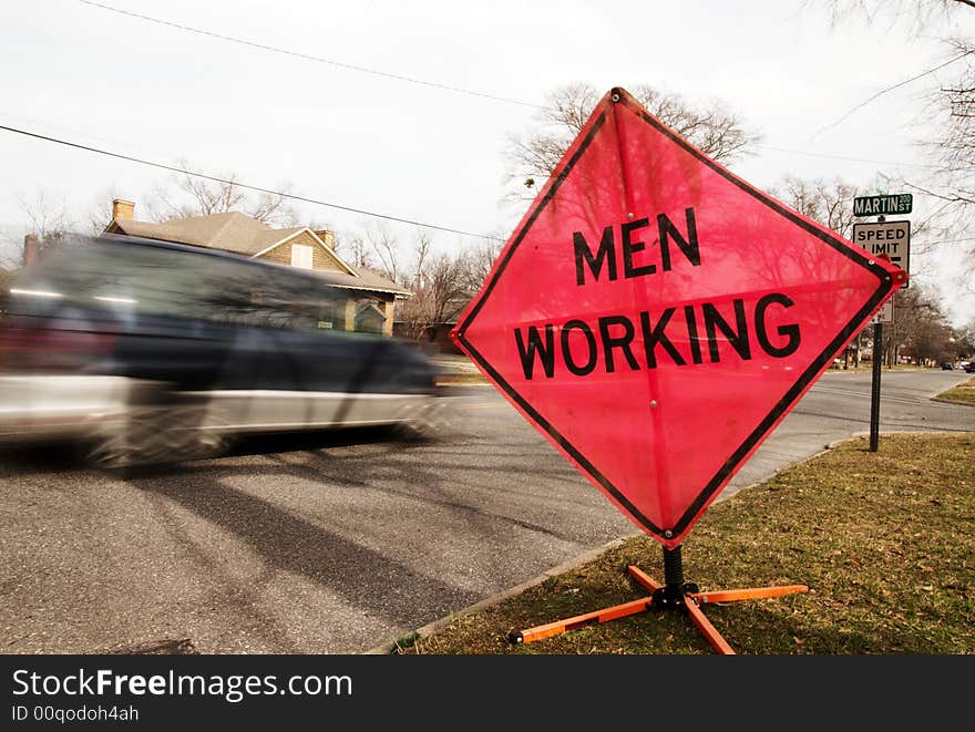 A men working sign by a busy street. A men working sign by a busy street.