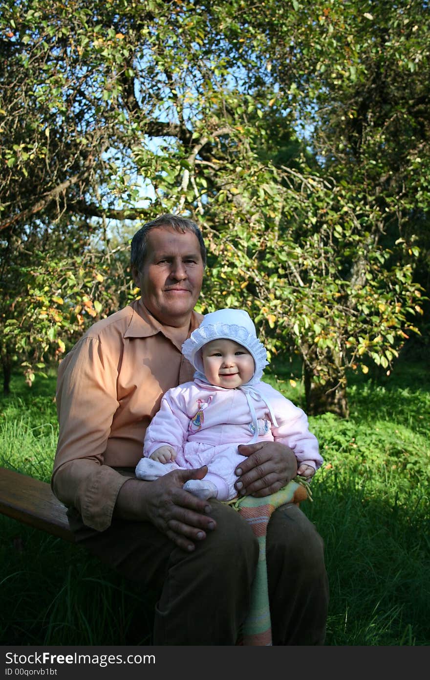 Grandfather and granddaughter sitting in the garden