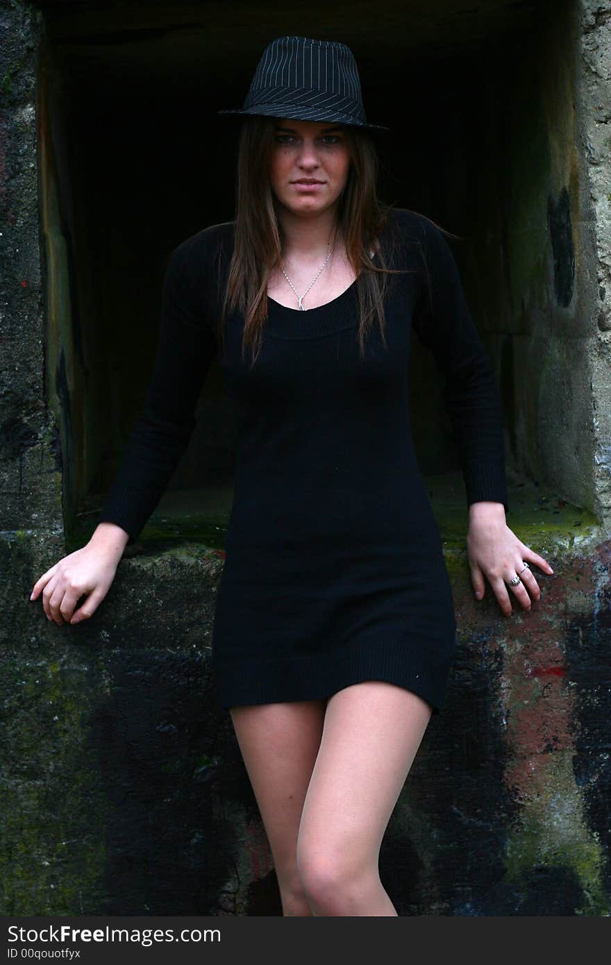 Young girl in the field on the warm winter day wearing black hat standing by the old military training path. Young girl in the field on the warm winter day wearing black hat standing by the old military training path