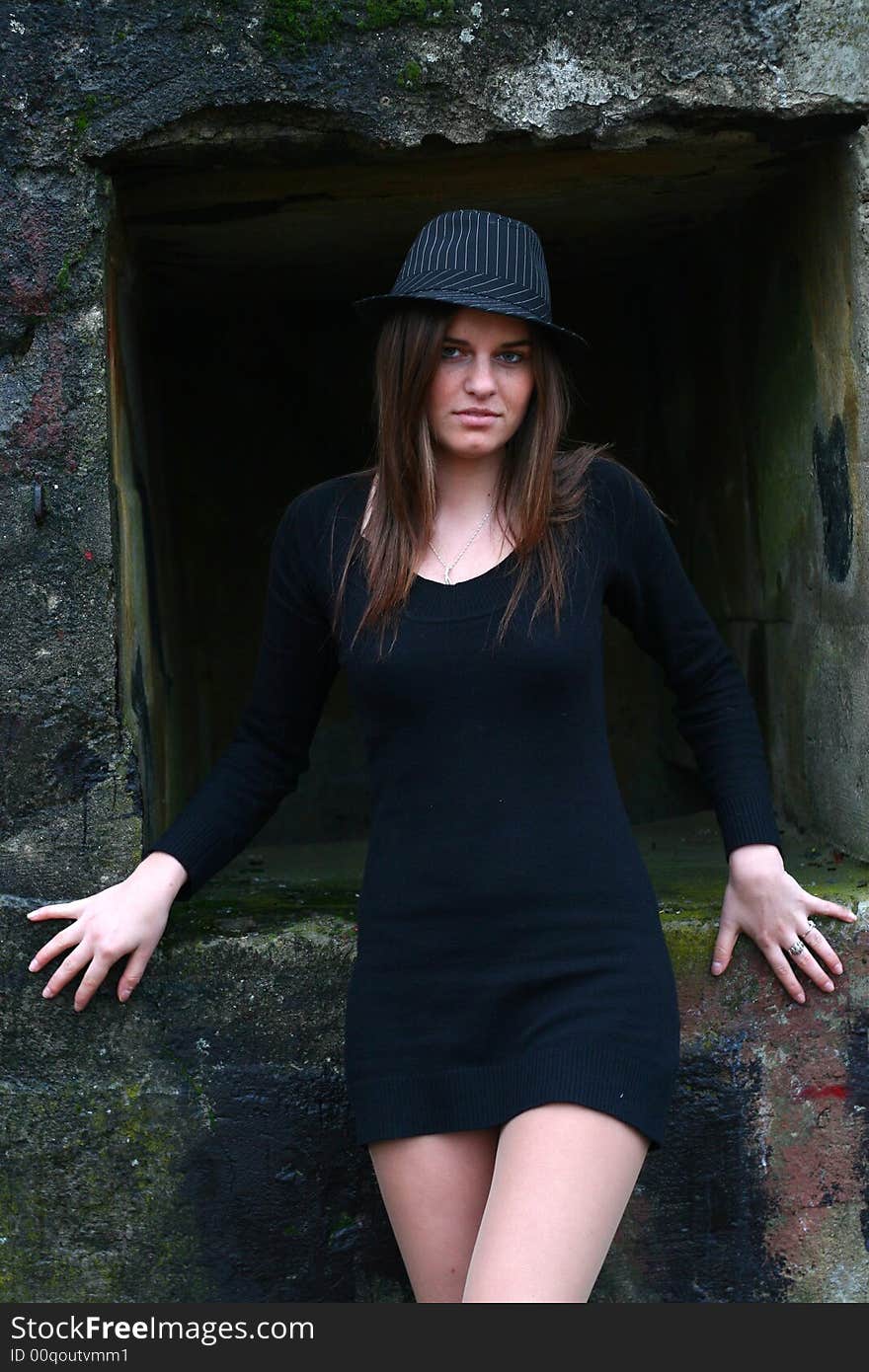 Young girl in the field on the warm winter day wearing black hat standing by the old military training path. Young girl in the field on the warm winter day wearing black hat standing by the old military training path