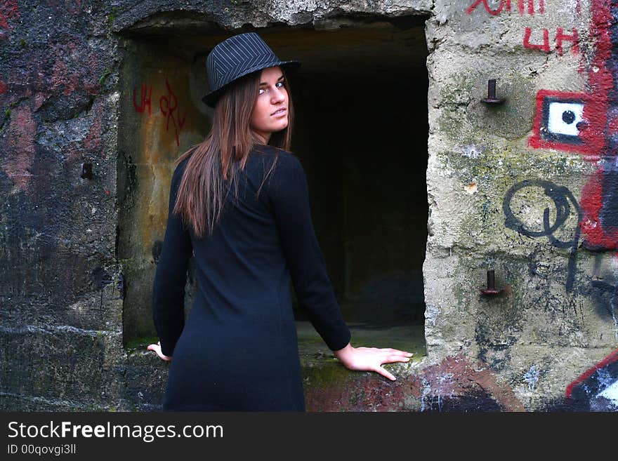 Young girl in the field on the warm winter day wearing black hat standing by the old military training path. Young girl in the field on the warm winter day wearing black hat standing by the old military training path