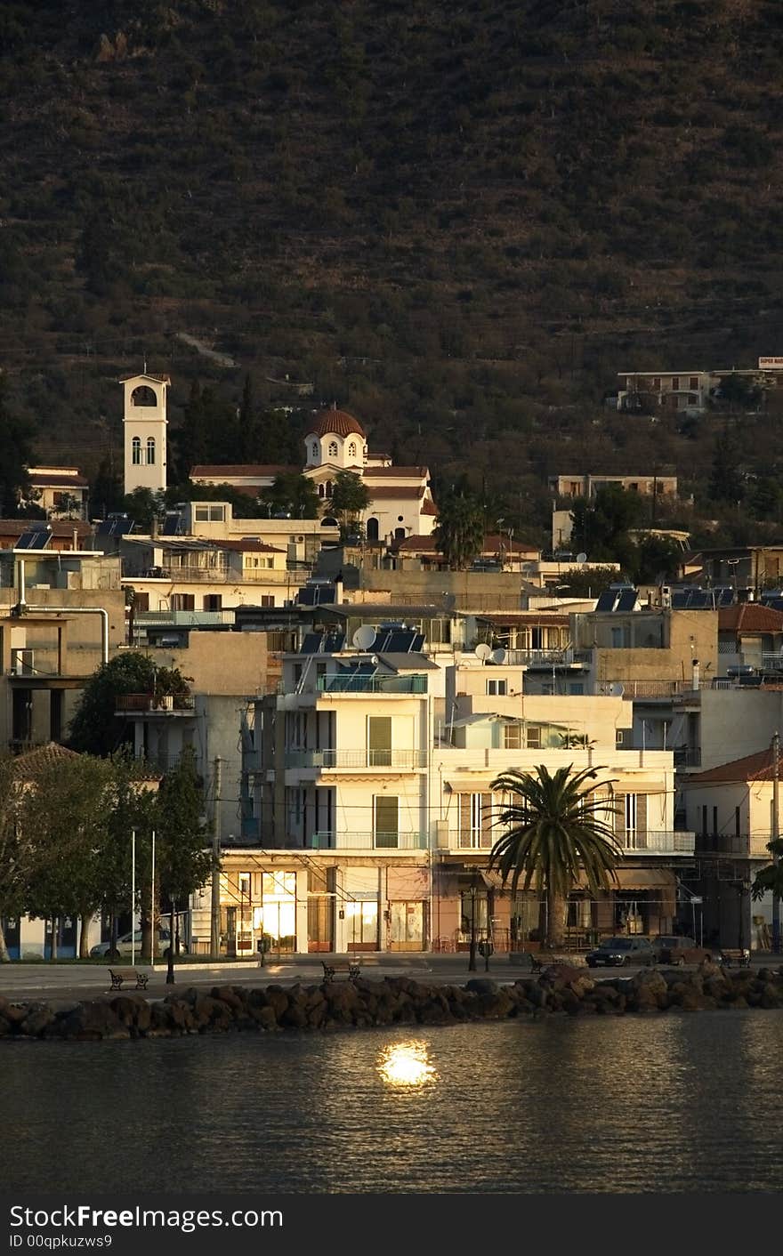 Sunrise in the Peloponnese town of Methana. The sun reflects from a window in the sea. Sunrise in the Peloponnese town of Methana. The sun reflects from a window in the sea