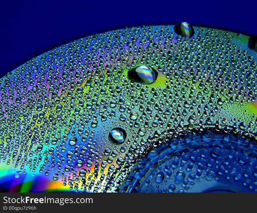 Full light spectrum on a cd quarter covered with water drops, blue background. Full light spectrum on a cd quarter covered with water drops, blue background