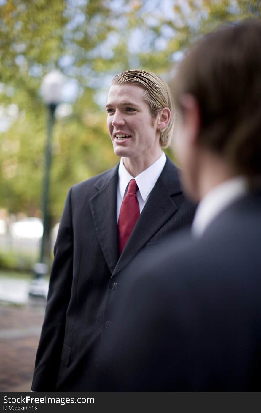 Over shoulder view of businessman standing in suit and tie talking. Over shoulder view of businessman standing in suit and tie talking