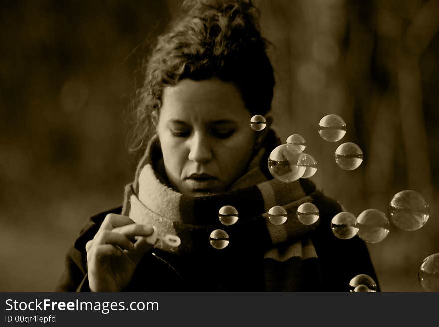 A young woman playing with soap bubbles (in sepia). A young woman playing with soap bubbles (in sepia)