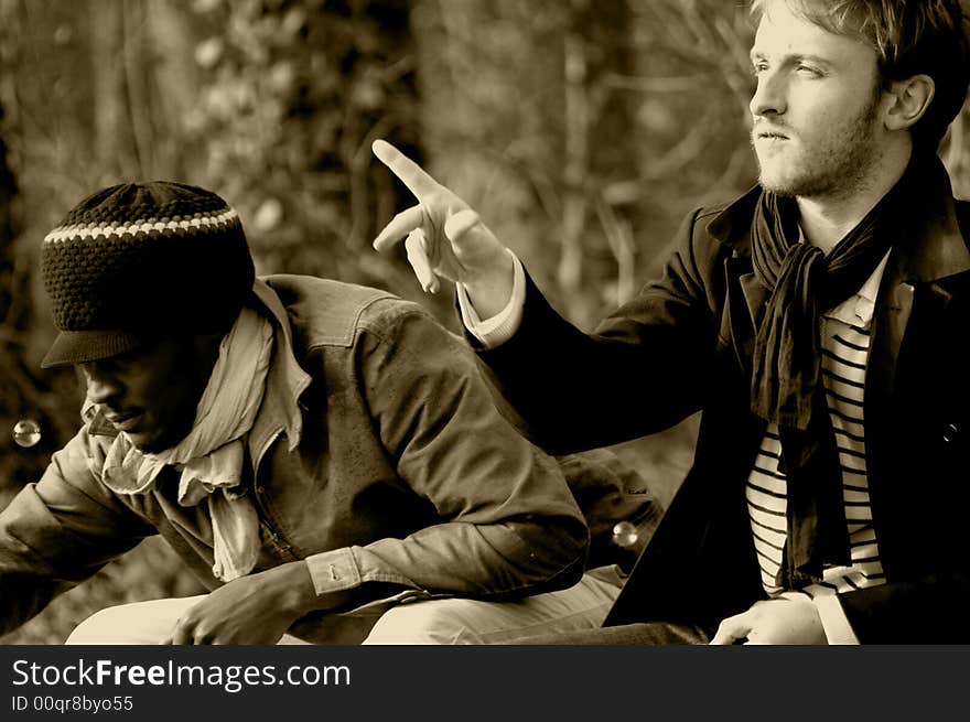 Portrait of two friends seated on a garden seat : a red-haired man and a rasta man. Portrait of two friends seated on a garden seat : a red-haired man and a rasta man.