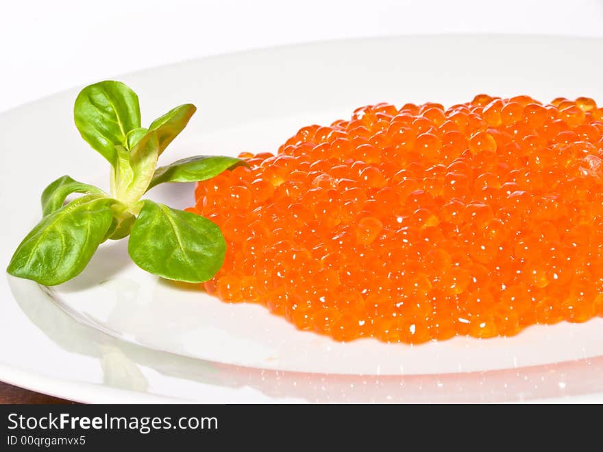 Red caviar served on a white plate. Close-up. White background. Red caviar served on a white plate. Close-up. White background.