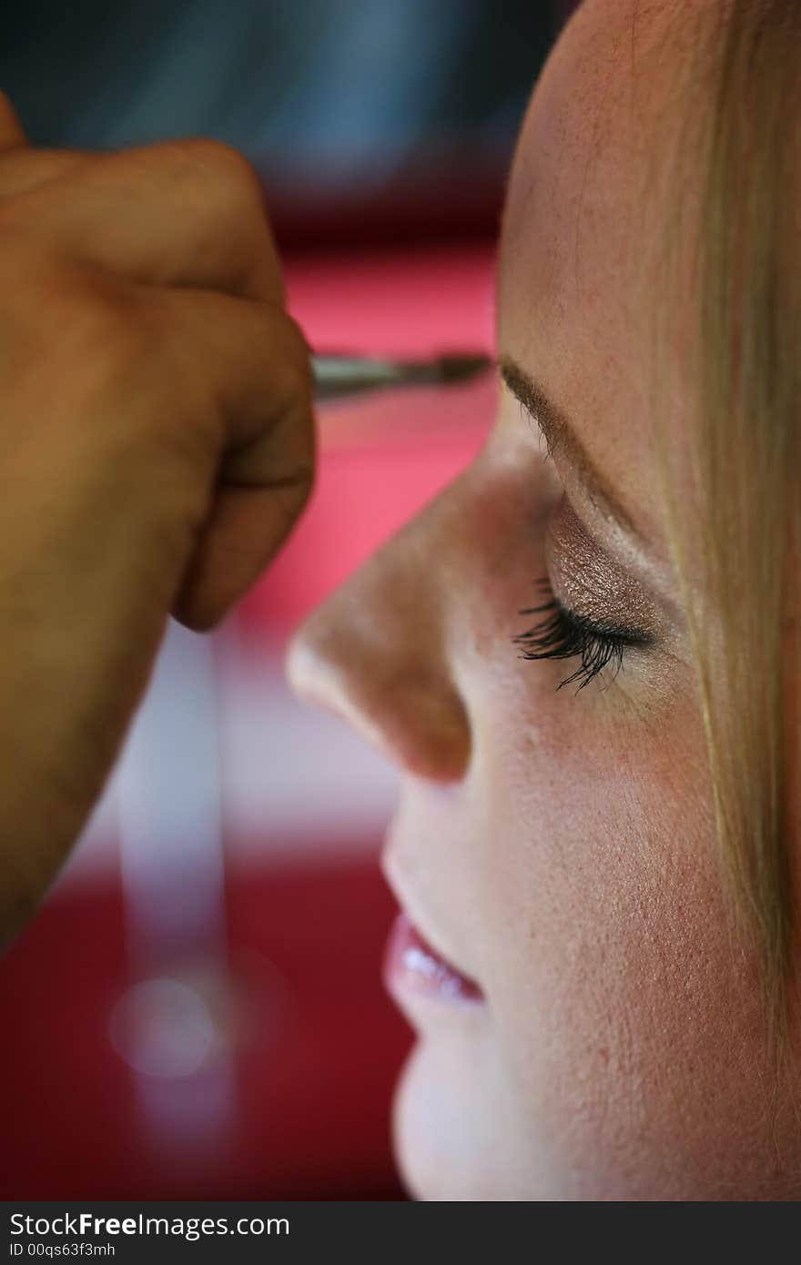 A young woman has makeup applied before a big event. A young woman has makeup applied before a big event