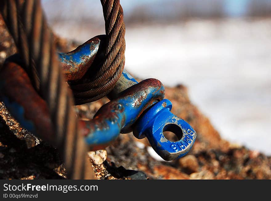 A rusted cable and shackle attached to a cement block.