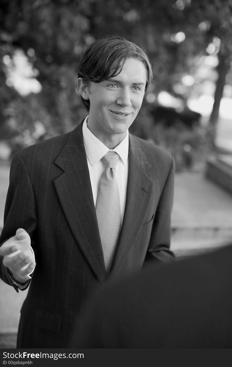 Over shoulder view of businessman standing in suit and tie talking. Over shoulder view of businessman standing in suit and tie talking