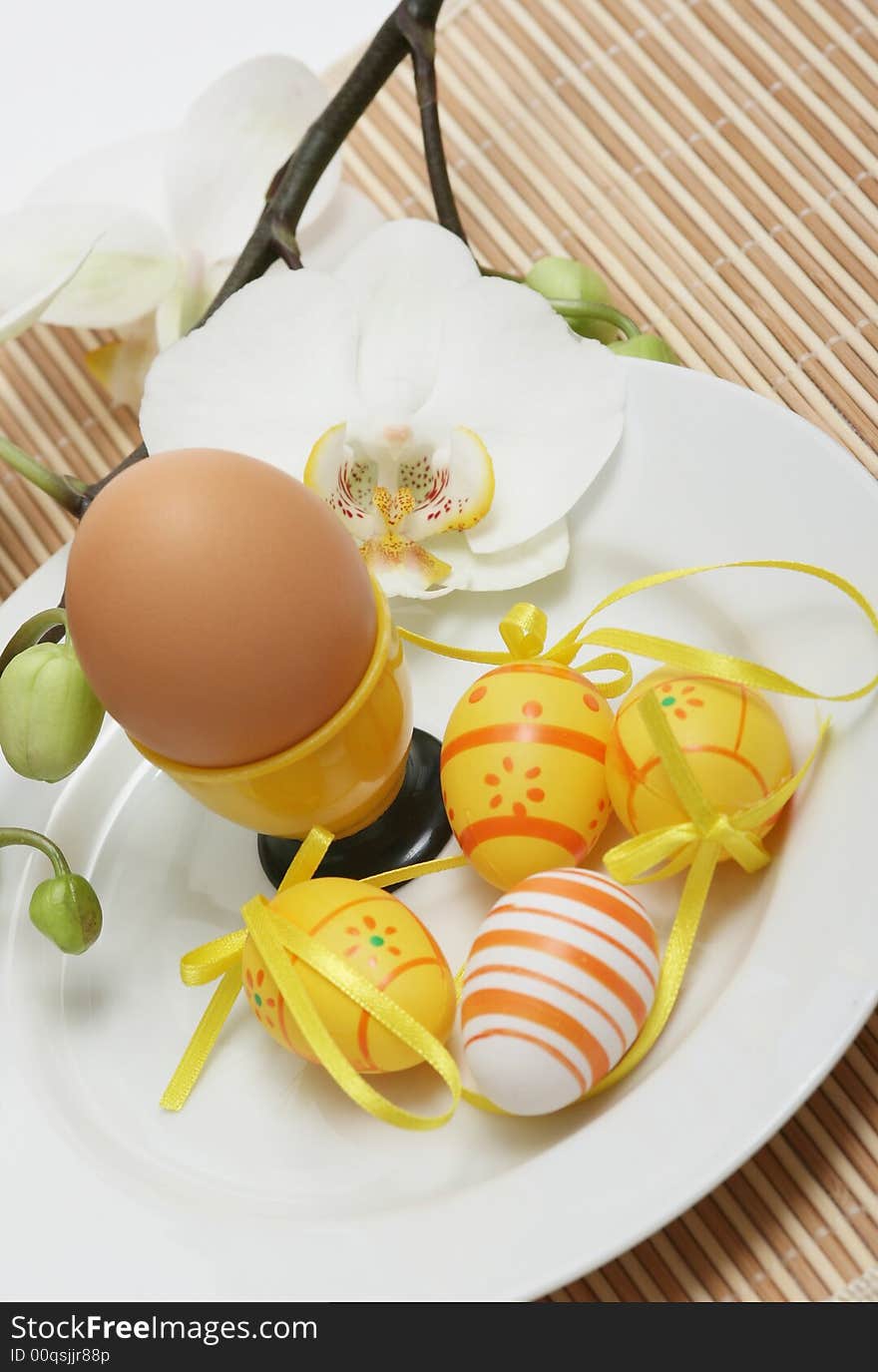 Nature egg with easter colored eggs and orchid on a table.