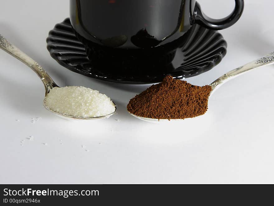 Two  tea-spoon with coffee and sugar infront of cofee-cup. Two  tea-spoon with coffee and sugar infront of cofee-cup